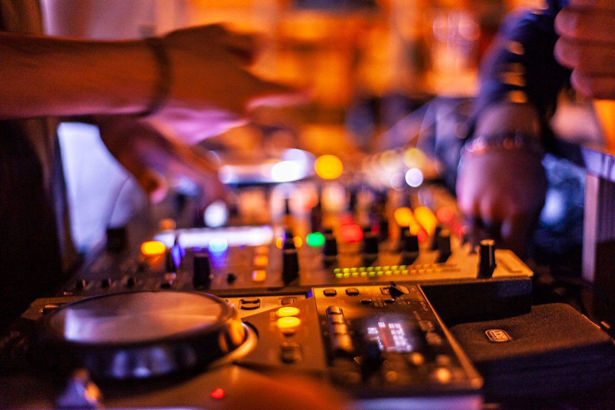 Hände eines DJs an einem beleuchteten Mischpult